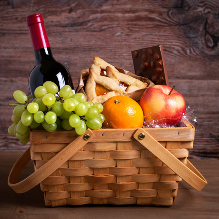 Purim basket, Purim gift with foods, cookies, fruits and wine on wooden table.の写真素材