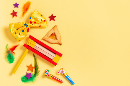 Purim carnival frame with traditional cookies, costume accessories and decor on bright yellow backgroundの写真素材
