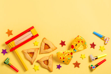 Purim carnival frame with traditional cookies, costume accessories and decor on bright yellow backgroundの写真素材