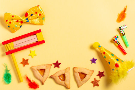 Purim carnival frame with traditional cookies, costume accessories and decor on bright yellow backgroundの写真素材