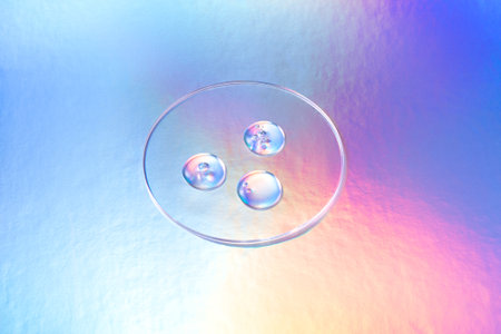 Facial serum drops, hyaluronic acid, collagen serum drops closeup on holographic backgroundの写真素材