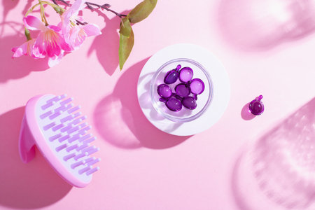 Scalp Massage and Cleansing Shampoo Brush with hair vitamins on pink backgroundの写真素材