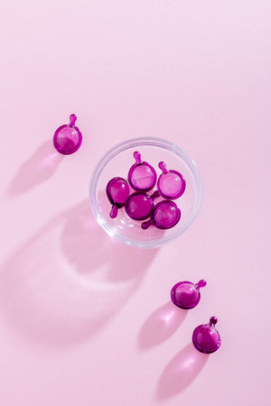 Vitamin capsules in pink, purple color, closeup on pink background, top viewの写真素材