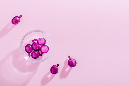 Vitamin capsules in pink, purple color, closeup on pink background, top viewの写真素材