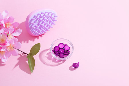 Scalp Massage and Cleansing Shampoo Brush with hair vitamins on pink backgroundの写真素材