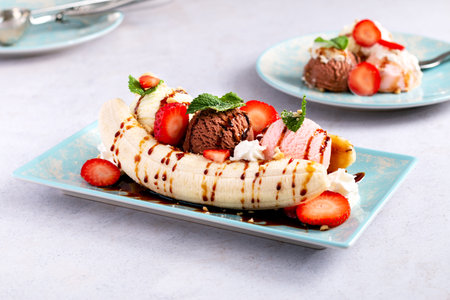 Banana split ice cream with syrup and strawberry on blue plate, top viewの写真素材