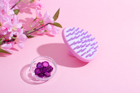 Scalp Massage and Cleansing Shampoo Brush with hair vitamins on pink backgroundの写真素材