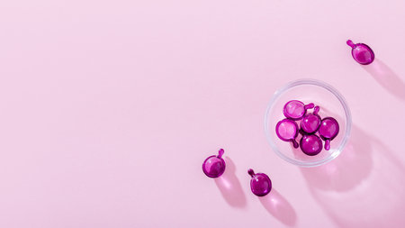 Vitamin capsules in pink, purple color, closeup on pink background, top viewの写真素材