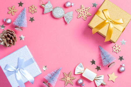 Christmas pink frame with golden gift box with mini Christmas trees and shiny baubles on pastel pink background, Christmas border, copy space. Christmas gift idea, holiday presents conceptの写真素材