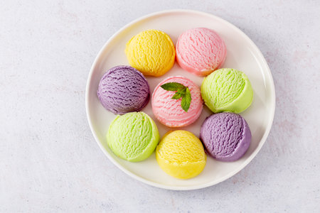 Pastel colored ice cream scoops on white plate, top view. Different flavor and color ice cream served on plate, copy space.の写真素材