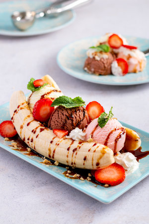 Banana split ice cream with syrup and strawberry on blue plate, top viewの写真素材