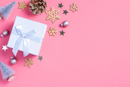 Christmas background with golden gift box with mini Christmas trees and baubles on pastel pink backgroundの写真素材