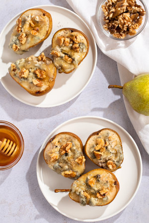 Baked pears with blue cheese, walnuts and honey on white plate and light backgroundの写真素材