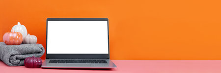 Blank screen laptop on table with minimal autumn or fall season decor, knit sweater, orange colors, seasonal business concept. Decorative ceramic pumpkins and open laptop still life, web bannerの写真素材