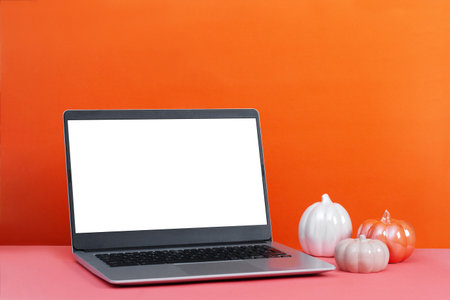 Laptop on table with minimal autumn or fall season decor, orange color, seasonal business conceptの写真素材