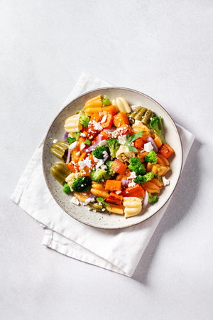 Autumn pasta salad with roasted pumpkin, broccoli, feta cheese on bright light background, fall season saladの写真素材