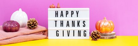 Lightbox with text Happy Thanksgiving with ceramic pumpkins on table, vivid color background.の写真素材
