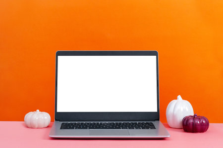 Laptop on table with minimal autumn or fall season decor, orange color, seasonal business conceptの写真素材