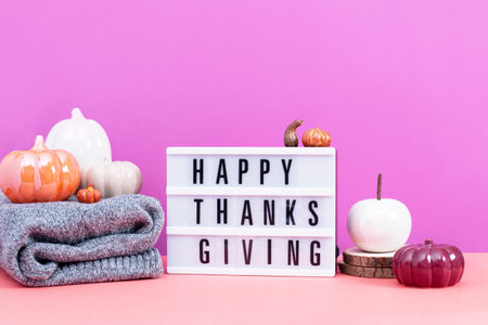 Lightbox with text Happy Thanksgiving with ceramic pumpkins on table, vivid color background.の写真素材