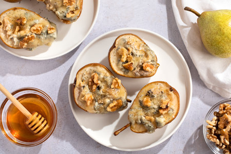 Baked pears with blue cheese, walnuts and honey on white plate closeup, perfect summer dish made of local fruits and affordable products, top viewの写真素材