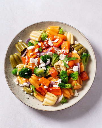 Autumn pasta salad with roasted pumpkin, broccoli, feta cheese on bright light gray background, vivid colors fall season salad, autumn food concept, top viewの写真素材