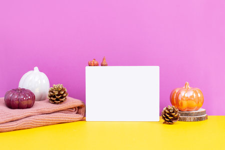Blank white card with ceramic pumpkins on table, vivid color background. Autumn or fall mock up with seasonal decor still life for autumn, fall, Thanksgiving or Halloween cards.の写真素材