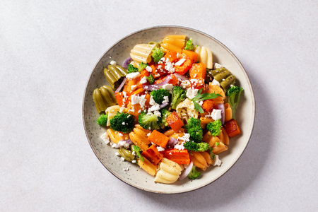 Autumn pasta salad with roasted pumpkin, broccoli, feta cheese on bright light gray background, vivid colors fall season salad, autumn food concept, top viewの写真素材
