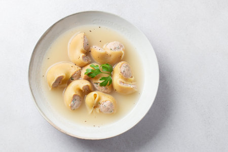 Traditional Catalan Christmas dish Escudella in white plate on table, stuffed pasta in meat broth, top view, copy spaceの写真素材