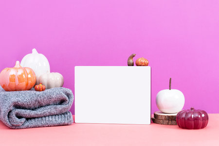 Blank white card with ceramic pumpkins on table, vivid color background. Autumn or fall mock up with seasonal decor still life for autumn, fall, Thanksgiving or Halloween cards.の写真素材