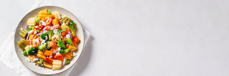 Autumn pasta salad with roasted pumpkin, broccoli, feta cheese on bright light background, fall season saladの写真素材
