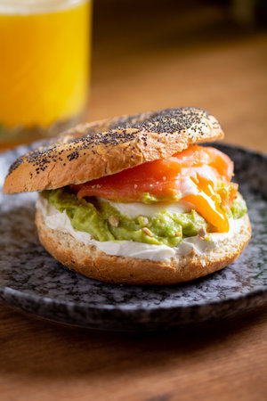 Bagel with poached eggs, cream cheese, avocado, and fish with juice. A cozy and nutritious breakfast or brunchの写真素材