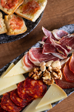 A top view of table in cozy cafe with plates of Catalan bread with tomato and olive oil, a selection of Spanish meatの写真素材