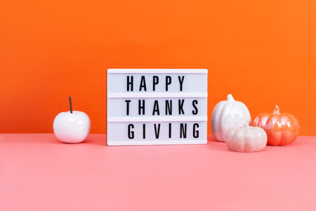 Lightbox with text Happy Thanksgiving with ceramic pumpkins on table, vivid color background. Autumn or fall mock up with seasonal decor still life.の写真素材