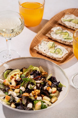 A fresh salad with feta, walnuts, apples, and crackers with cucumber and tsasiki, accompanied by orange juiceの写真素材
