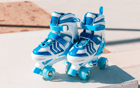 Two blue and white roller skates standing side by side on a concrete platform in an outdoor setting