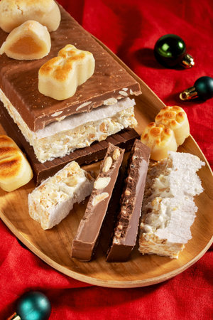 A wooden platter with traditional Spanish Christmas sweets: turron in various flavors and marzipan,...
