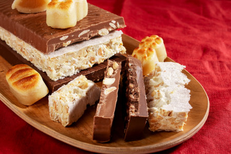 A wooden platter with traditional Spanish Christmas sweets: turron and marzipan on a beige stone backgroundの写真素材