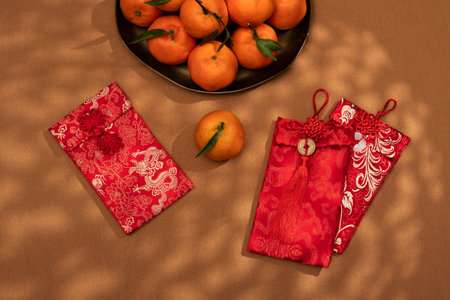 A plate of oranges and red gift envelopes on a beige table, symbolizing the Chinese New Year celebration and traditionsの写真素材