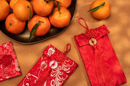 A plate of oranges and red gift envelopes on a beige table, symbolizing the Chinese New Year celebration and traditionsの写真素材