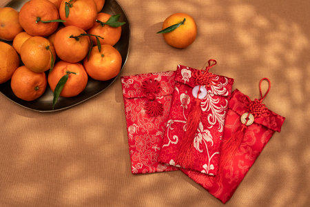 A plate of oranges and red gift envelopes on a beige table, symbolizing the Chinese New Year celebration and traditionsの写真素材