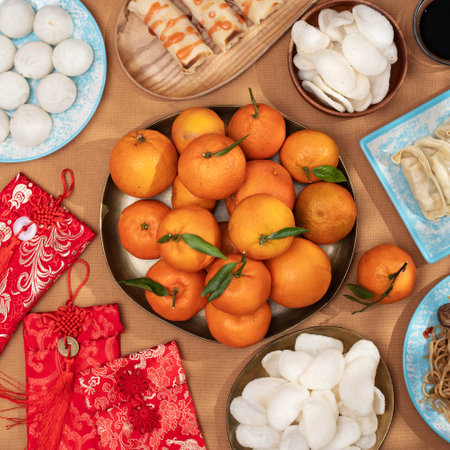 Traditional Chinese New Year food arrangement on a table, featuring dumplings, noodles, oranges with red envelopes for gifts, top viewの写真素材