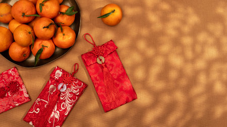 A plate of oranges and red gift envelopes on a beige table, symbolizing the Chinese New Year celebration and traditionsの写真素材