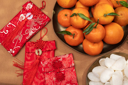 A plate of oranges and red gift envelopes on a beige table, symbolizing the Chinese New Year celebration and traditionsの写真素材