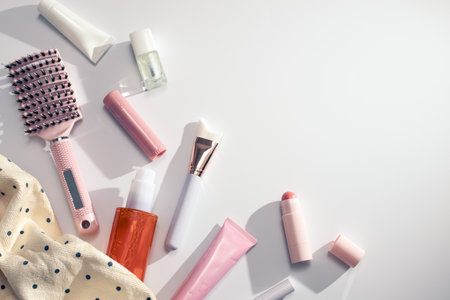 Beauty products background border flat lay with flowers, skincare, haircare and makeup items white background filled with shadows, spring skincare, top view, copy spaceの写真素材