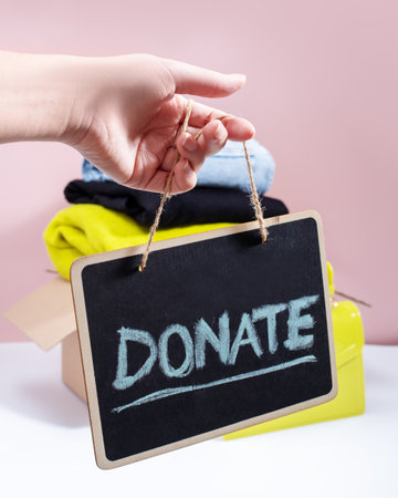 Donate sign on a blackboard with clothes and accessories in backgroundの写真素材
