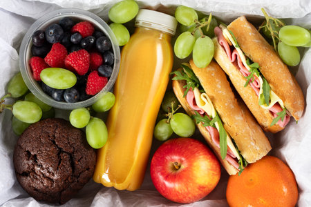 Ready prepared brunch box with sandwiches, fruits, berries and smoothie. Quick lunch break, time saving healthy mealの写真素材