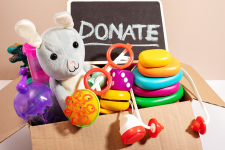Toys for children in a box with a Donate sign on beige, minimal style. Concept of toys donations, charity for childrenの写真素材