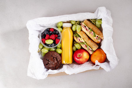 Ready prepared brunch box with sandwiches, fruits, berries and smoothie. Quick food to eat on the go or for lunch break, time saving ready to eat healthy meals, top viewの写真素材