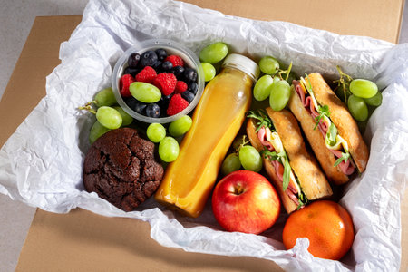 Ready prepared brunch box with sandwiches, fruits, berries and smoothie. Quick food to eat on the go or for lunch break, time saving ready to eat healthy meals, top viewの写真素材