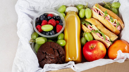 Ready prepared brunch box with sandwiches, fruits, berries and smoothie. Quick food to eat on the go or for lunch break, time saving ready to eat healthy meals, top viewの写真素材